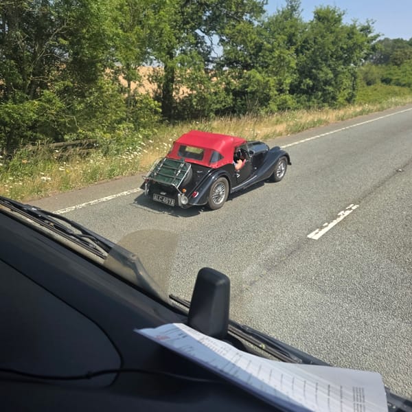 Classic black convertible with luggage rack rolling through Naseby