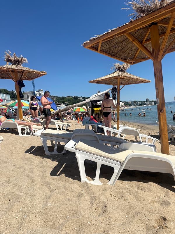 Crowded sunny beach with chairs, umbrellas, and flags