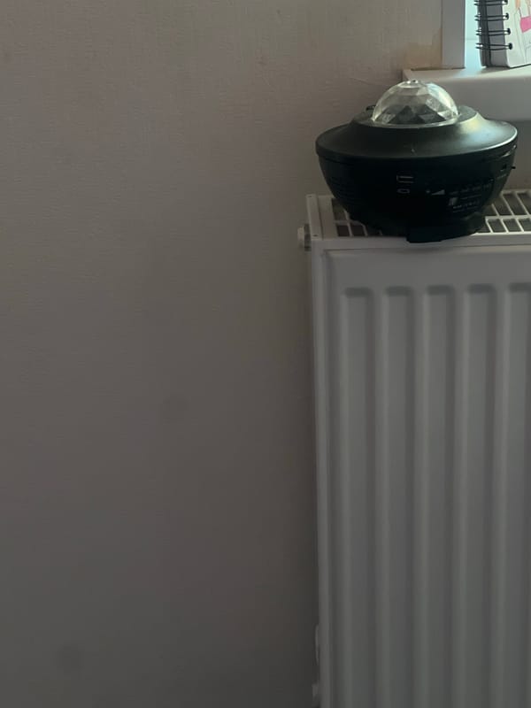 Star projector spotted on radiator against grey wall