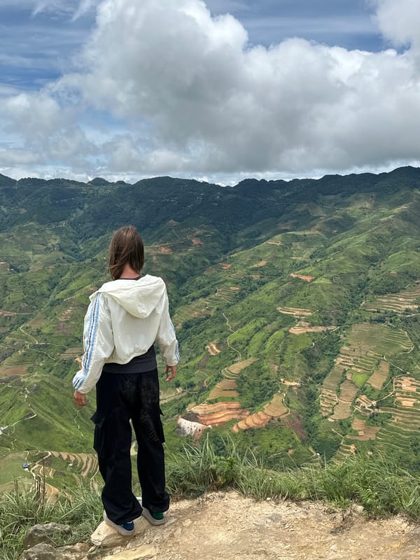 Person in striped jacket views terraced landscape at Ta Xua