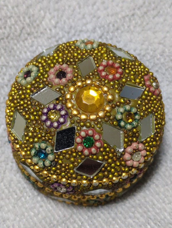 Ornate circular object with gold beads captured overhead