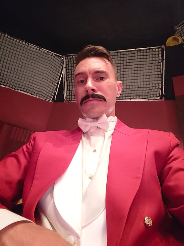 Man in formal red attire spotted under ornate chandelier
