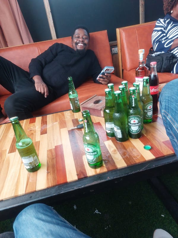Man relaxes with phone at outdoor bar in Dar es Salaam
