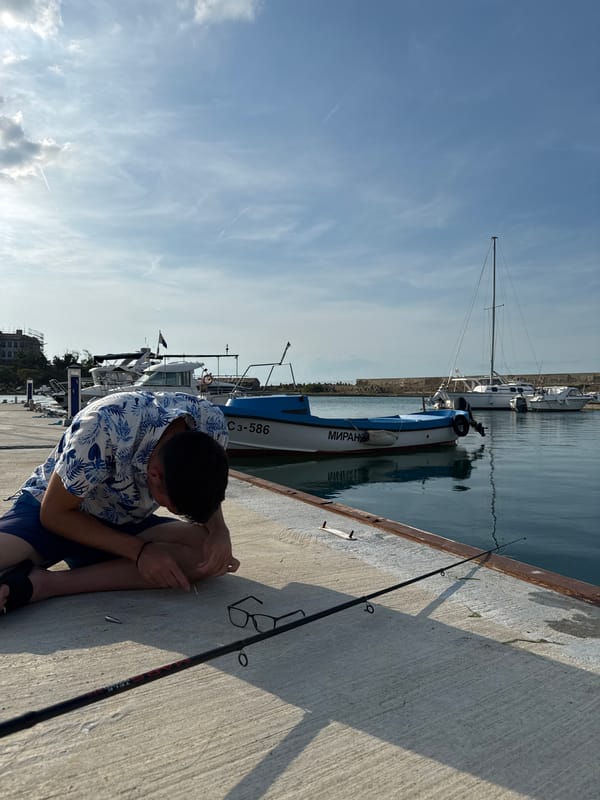 Young man fishing, kitten playing captured in Sozopol marina