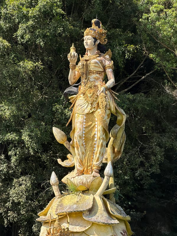 Golden statues rise from a green lake at Kintamani temple complex