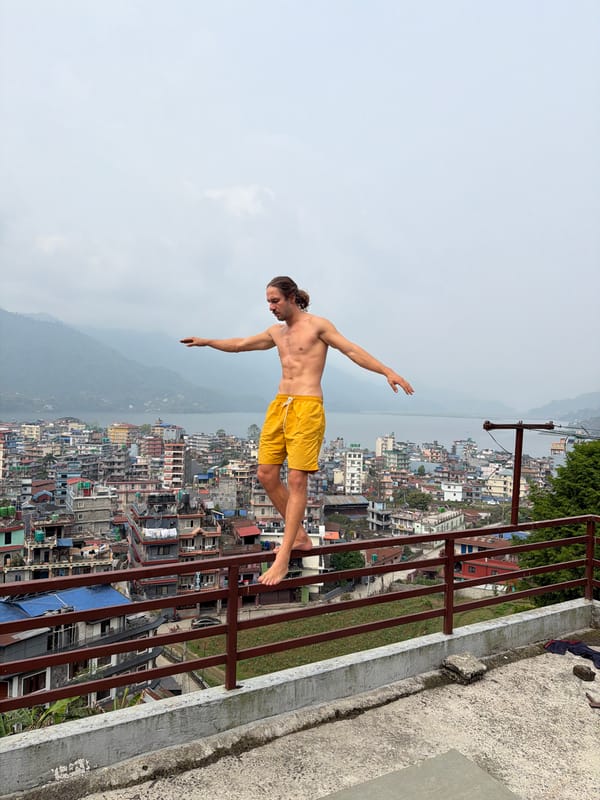Man balances on rooftop railing overlooking Pokhara Nepal