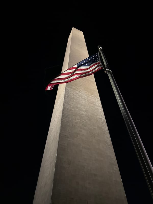 Washington Monument photographed illuminated at night with American flag