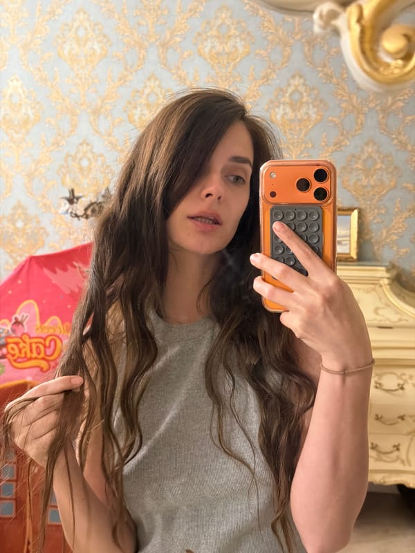 Indoor selfie with orange phone against ornate wallpaper in Ufa
