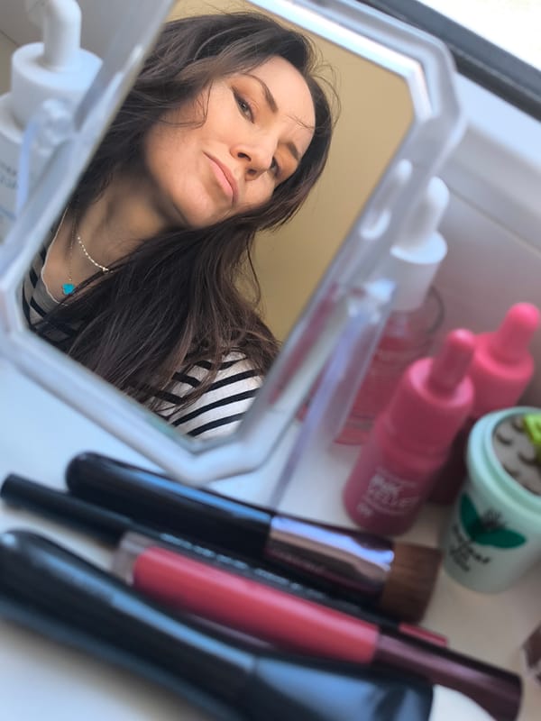 Woman applies makeup in mirror, Riga Latvia morning routine