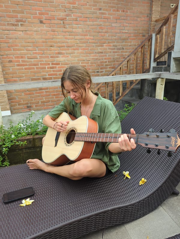 Woman plays guitar outdoors in North Kuta amid poolside setting