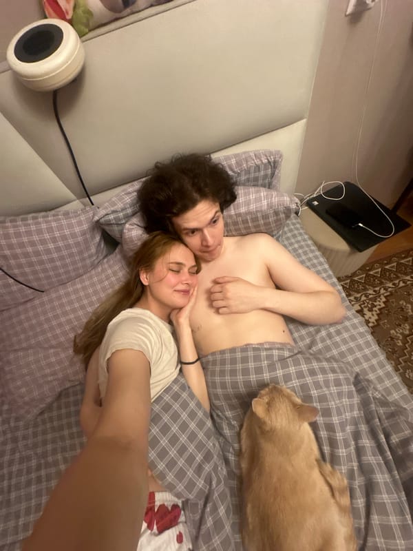 Couple and cat share lazy afternoon in Krasnoyarsk bedroom