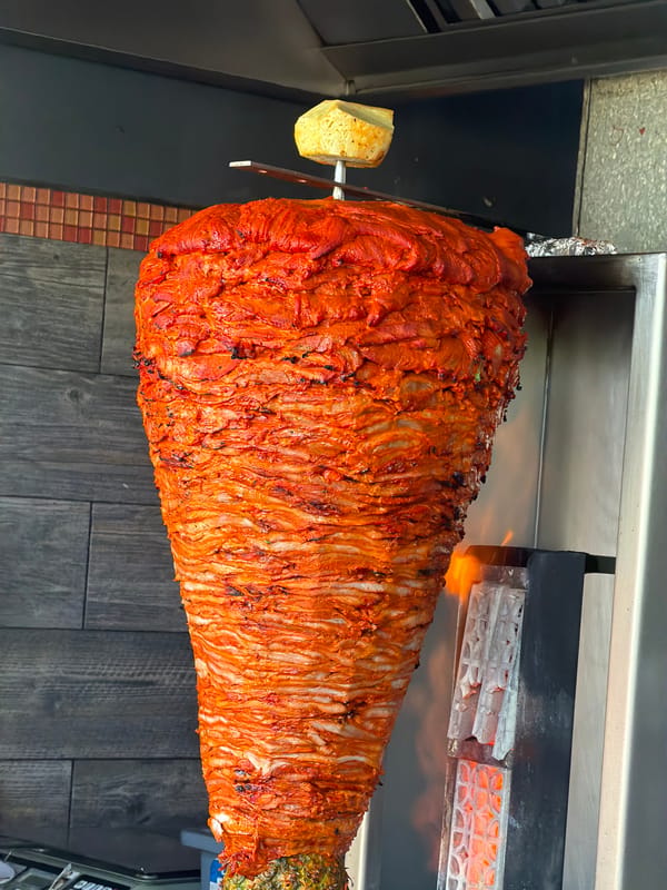 Al pastor trompo in action at a busy Cancún taqueria