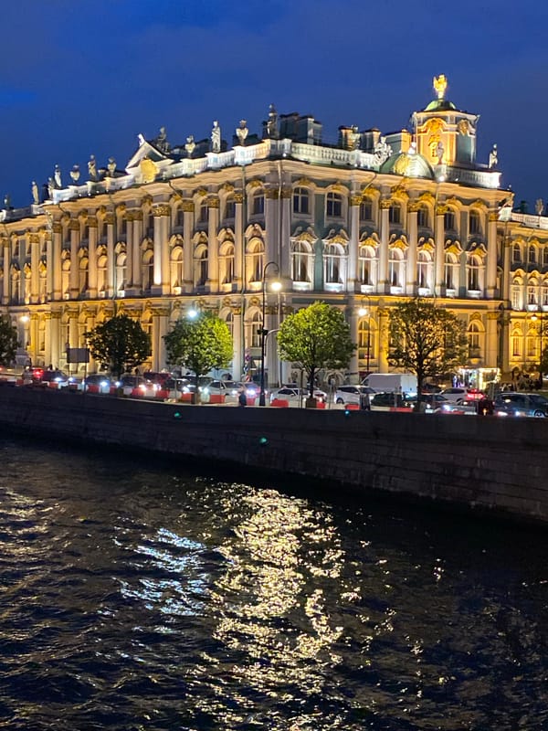 Winter Palace glowing at night across the Neva River