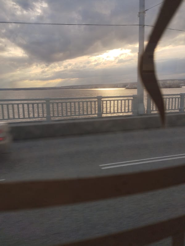 Vehicle crosses bridge over water with sunlight reflections