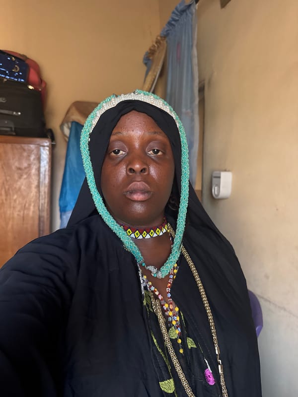 Woman in traditional dress displays jewelry in Madangala