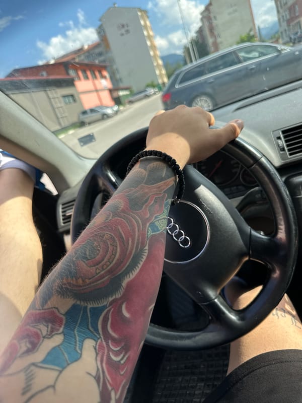 Driver with tattooed arm navigates sunny streets in Samokov