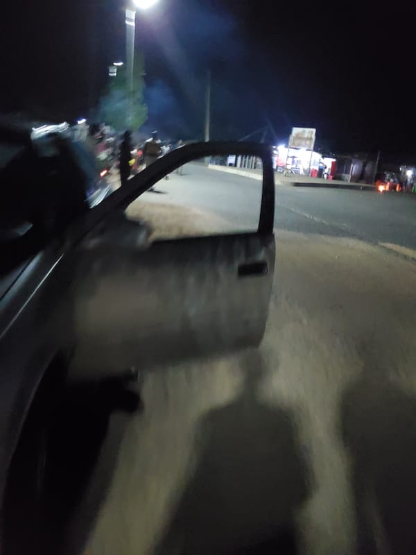 Nighttime street and market activity along a Jalingo commercial strip