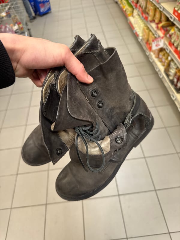 Person holds worn leather boots in Les Ulis store
