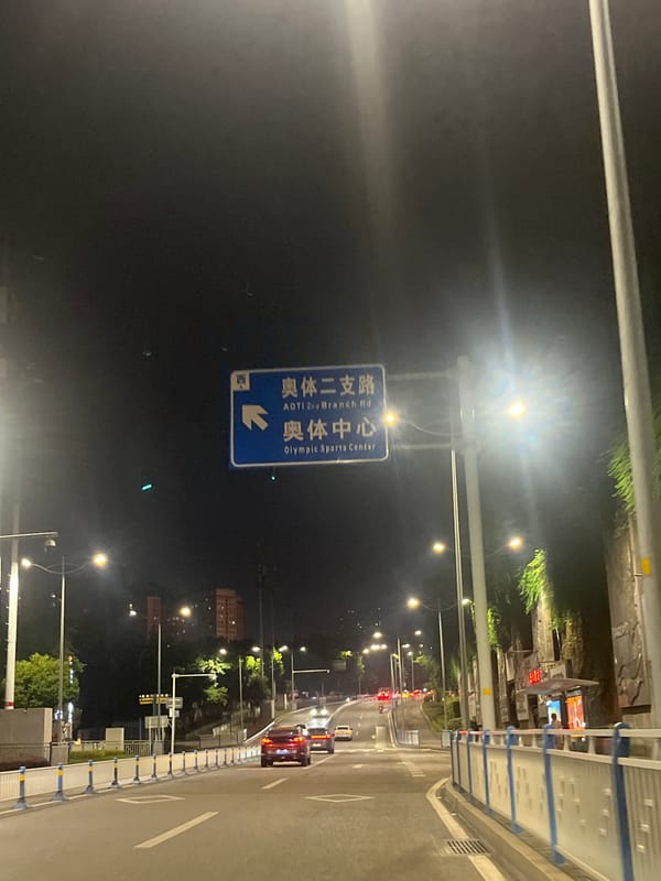 Nighttime scooter traffic documented on Chongqing streets near Olympic Sports Center
