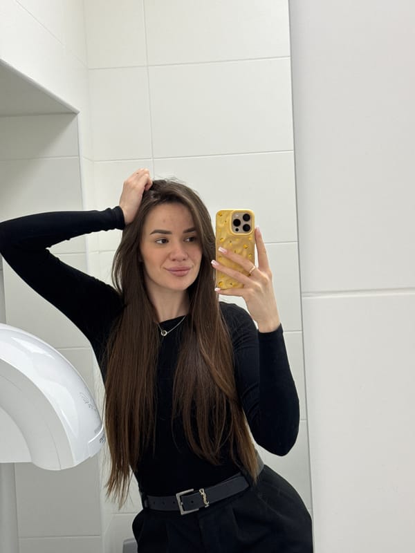 Back-to-back selfies in a restroom and elevator, same black outfit.