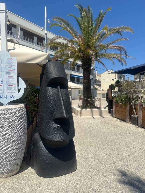 Sunny beach day near a coastal hotel with Moai statues nearby