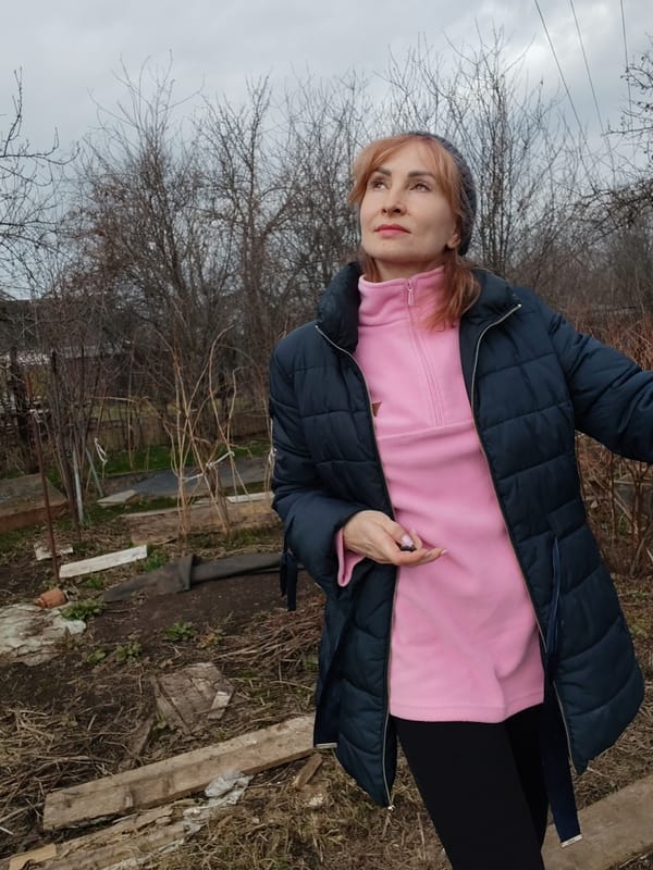 Woman tends spring garden amid industrial Chaikovsky streetscape