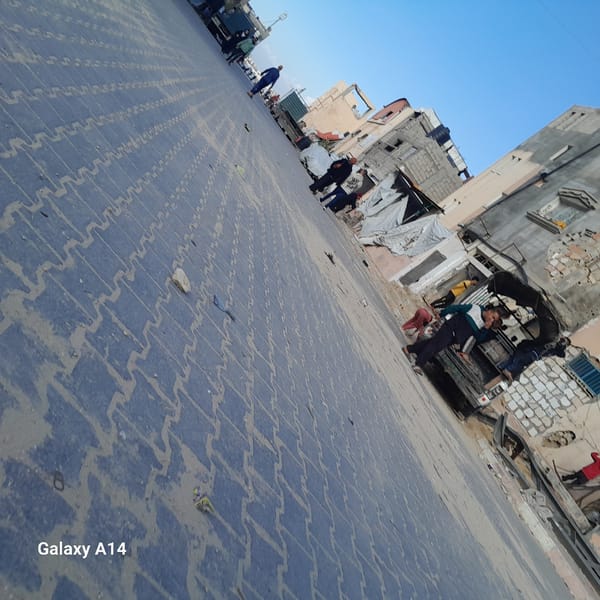 Pedestrians navigate paved streets in Khan Yunis under clear skies