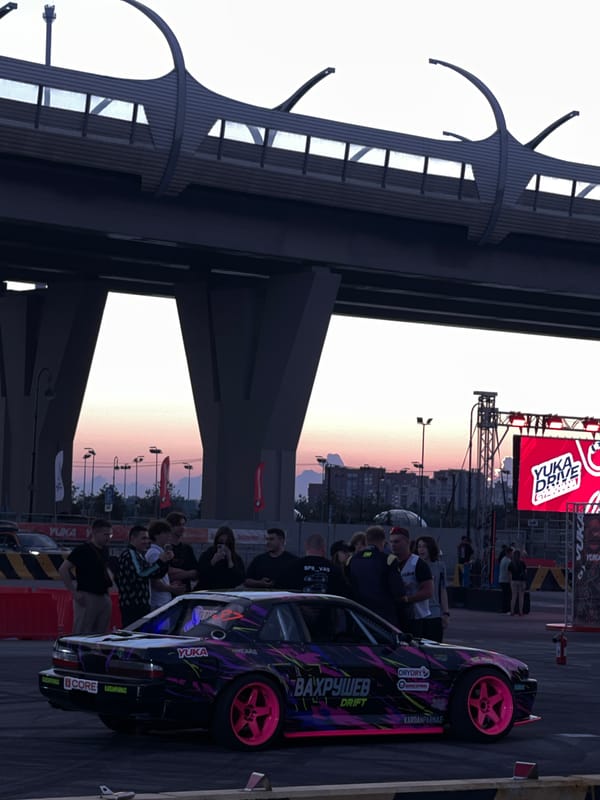 Urban drift meet draws modified cars under a highway overpass at dusk
