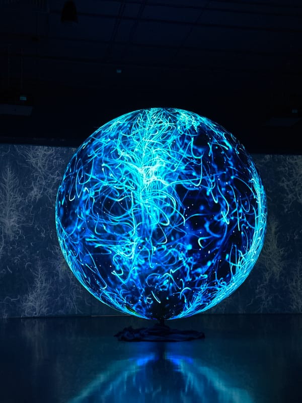 Glowing spherical display cycles through animated blue visuals indoors