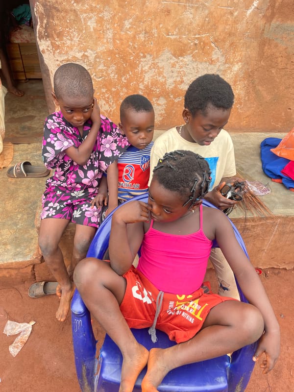 Children gather outdoors, drink water in Ogbe Nigeria morning