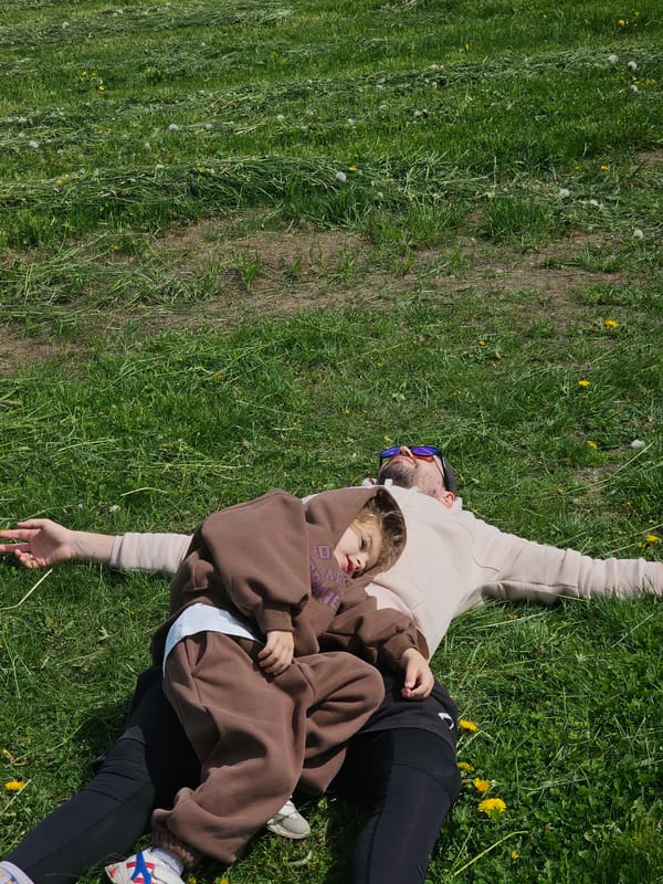 Man and child rest on dandelion-dotted grass in Russia