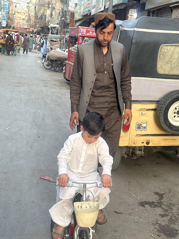 Child operates red vehicle near street vendor in Quetta