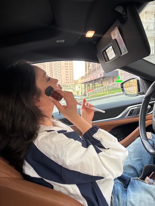 Woman applies makeup in car passenger seat in Armenia