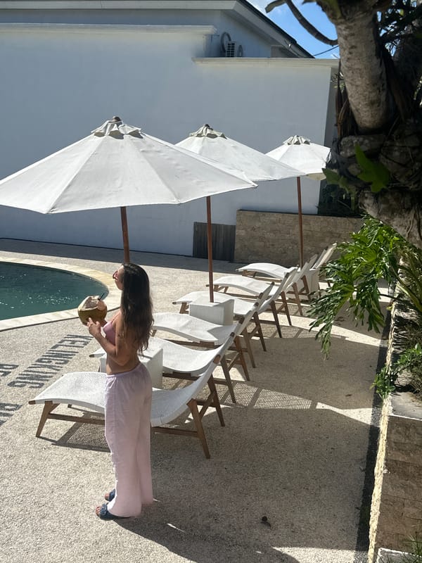 Woman enjoys coconut drink poolside in Nusa Penida morning