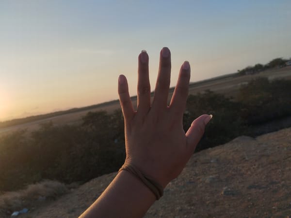Hand gesture photographed against sunset sky in Venezuelan coastal town
