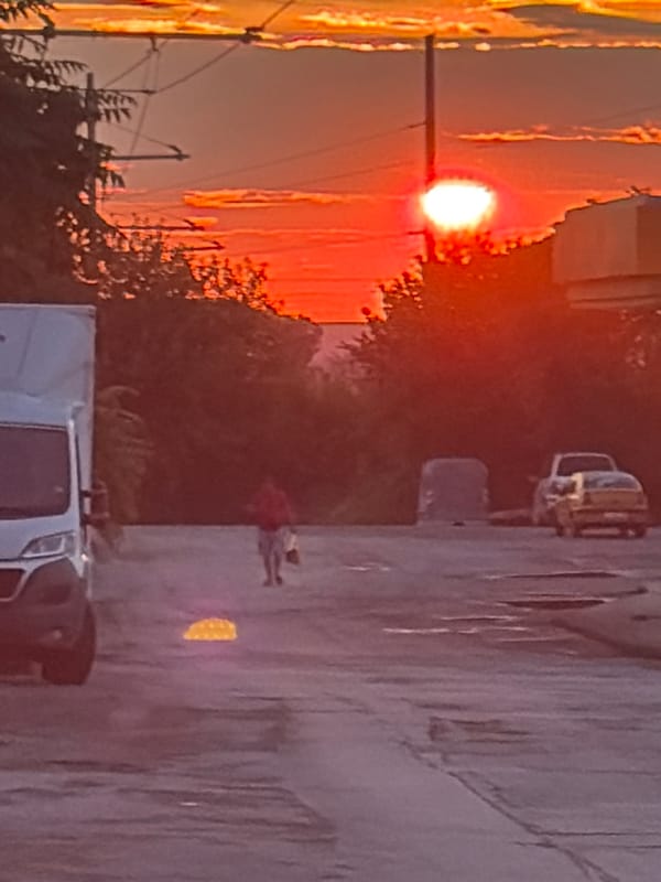 City street walk under a fiery orange sunset sky