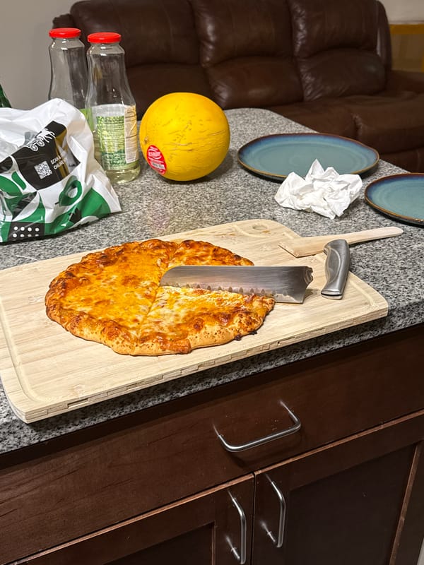 Fresh cheese pizza being sliced on a wooden board in Fife