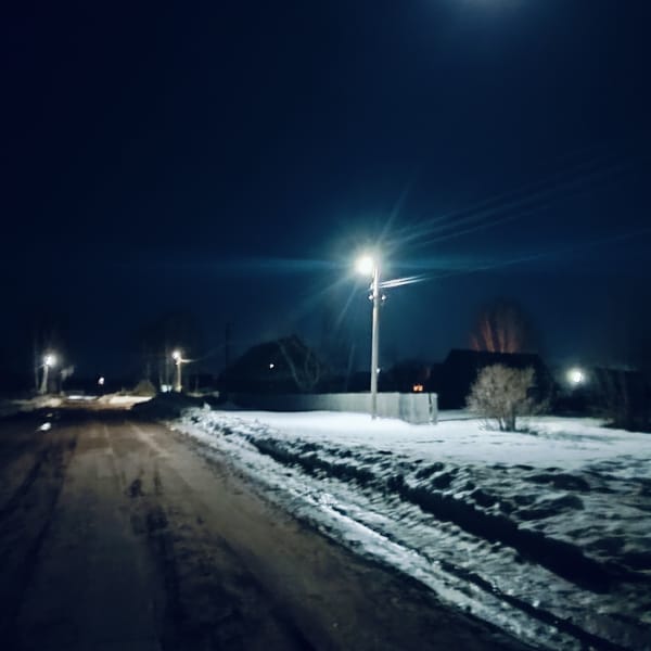 Muddy road illuminated by streetlights in snowy Буренка, Russia