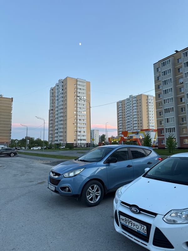 Daytime crescent moon visible over Tobolsk apartment complex