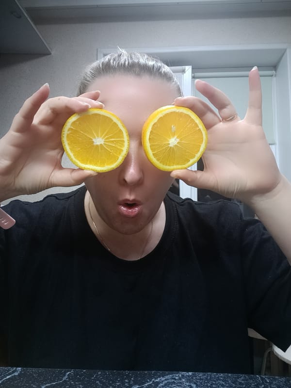 Woman poses playfully with orange slices in Russian kitchen