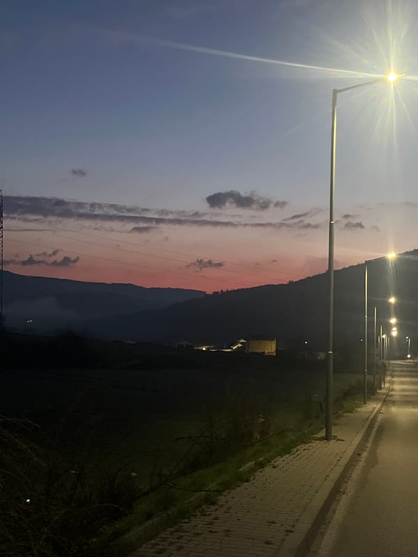 Nighttime streetlights illuminate roadside path in Velingrad, Bulgaria
