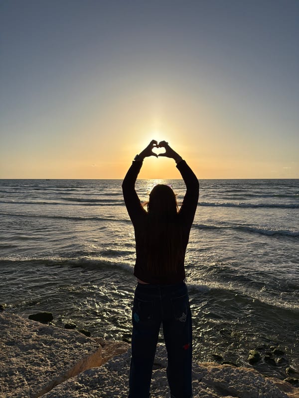 Woman writes in notebook amid flowers in Tel Aviv