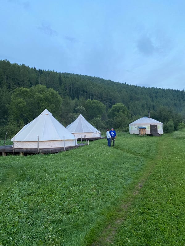 Bell tents, a yurt, and a drone at a rural dusk campsite