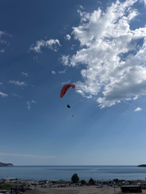Paragliders soar over Montenegro coast during afternoon leisure hours