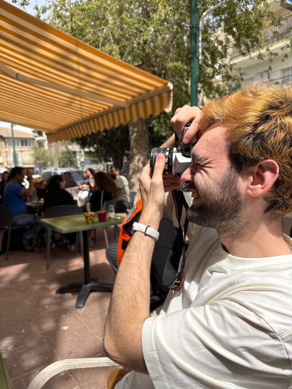 Man with vintage camera captured amid artwork and cake