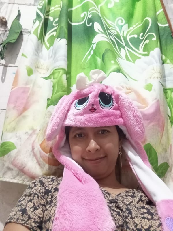 Person in Pink Rabbit Hat Rests on Floral Bedding