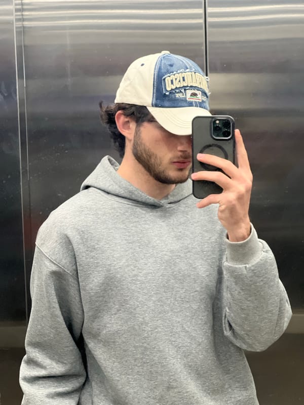 Man takes selfie in Yerevan elevator wearing hoodie and cap