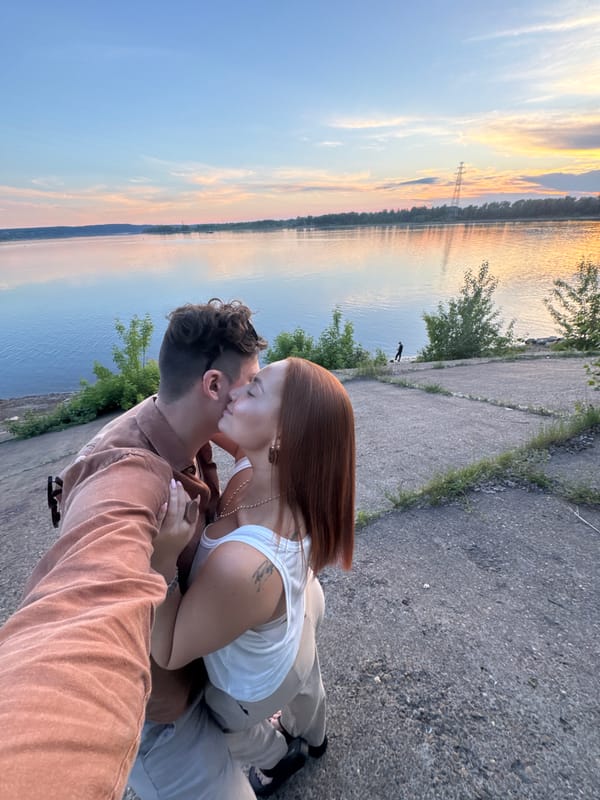 Couple shares romantic sunset moment by Russian riverside lighthouse