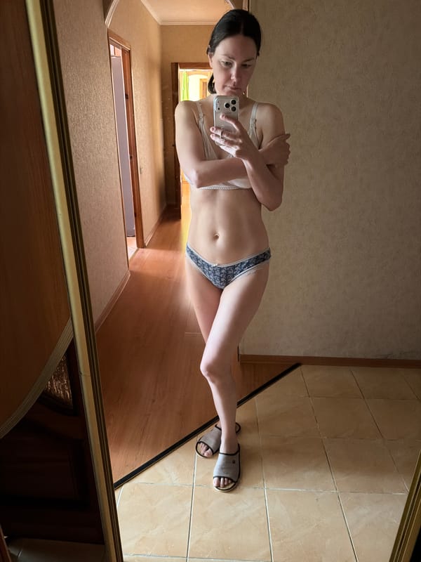Woman takes mirror selfie in residential hallway setting