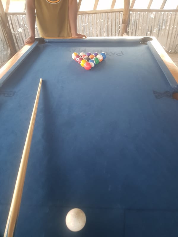 Pool game at a rustic open-air billiard table